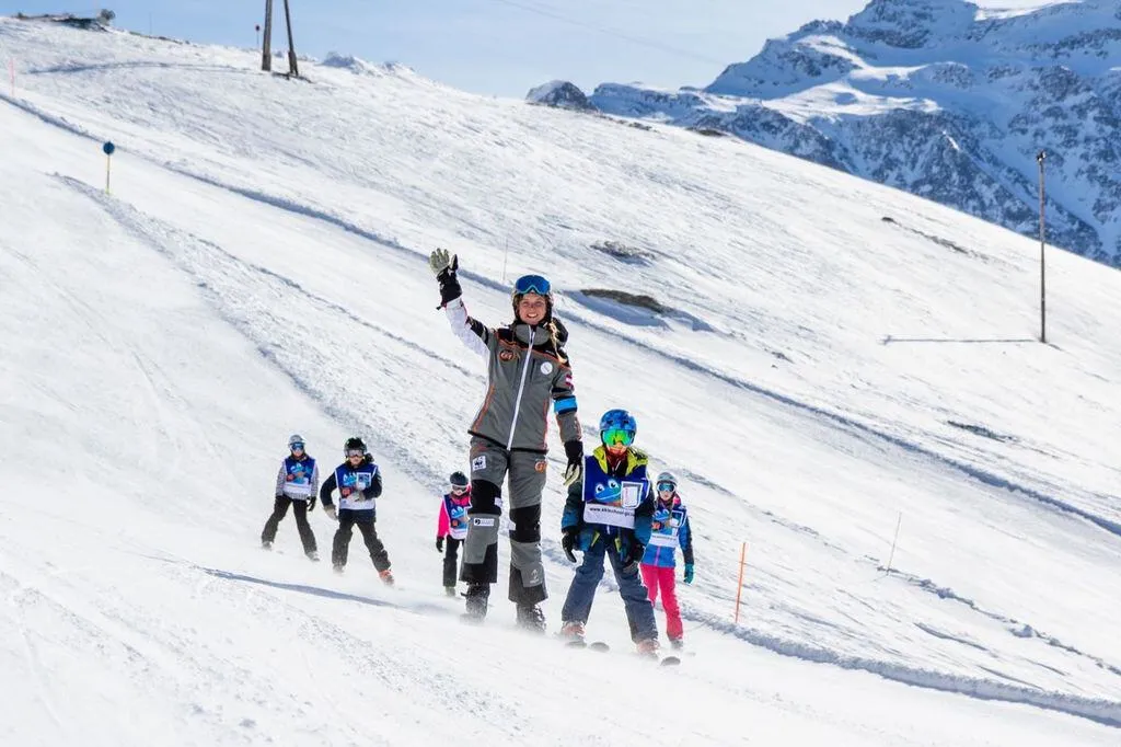 An instructor skiing with kids